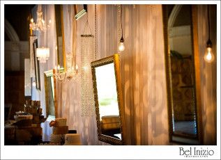 Heirloom Wall of Ivory Taffeta Drapery with Assorted Mirrors, Edison Bulbs, Crystal Chandeliers, Shade Lamps, and GOBO Patterns