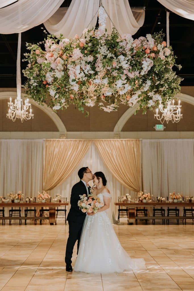 Kevin and Connie sharing a moment during their wedding reception at Casa Real under a flower 
chandelier 