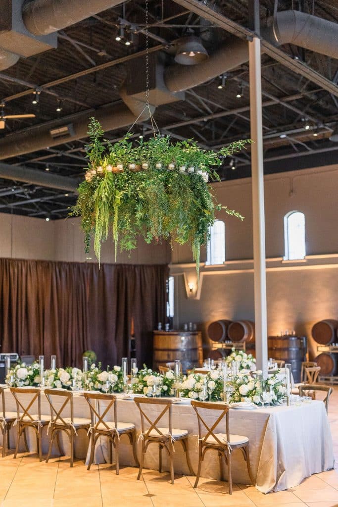 Chandelier with greenery over reception tables