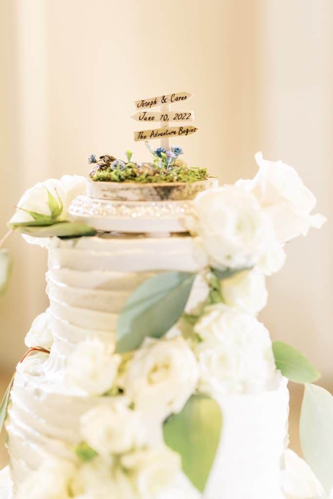 A white wedding cake with white flowers and greenery