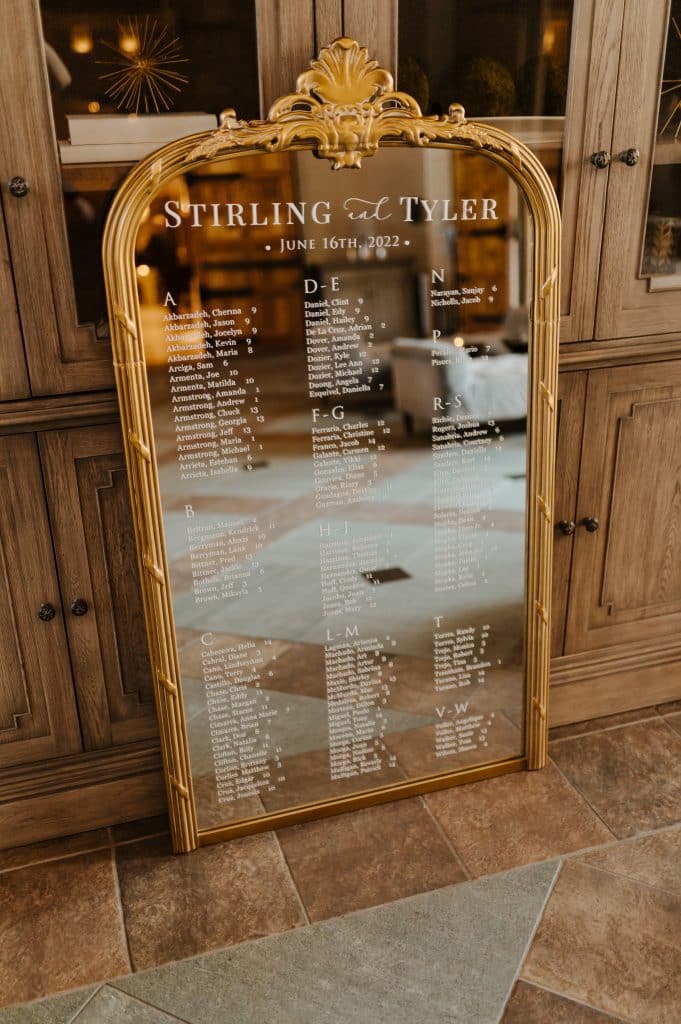 large gold mirror with calligraphy for a wedding seating chart