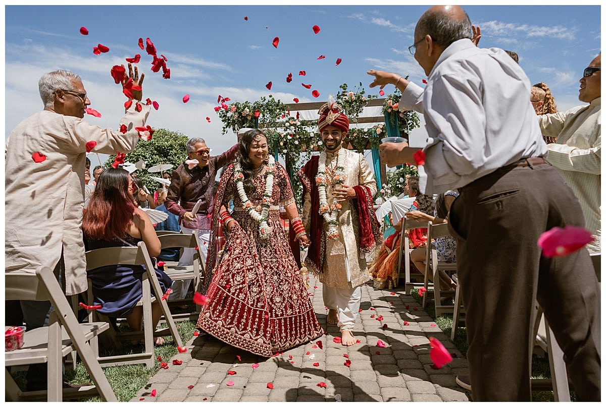 processional of Nancy and Aakash with roses petals being thrown